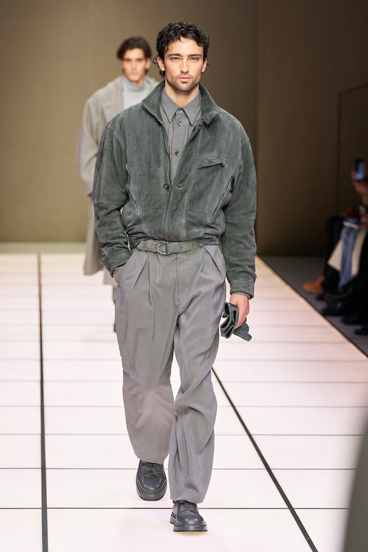 Мужская модель в мягком сером замшевом куртке и брюках, гармонирующих по цвету, с акцентом на стильные детали