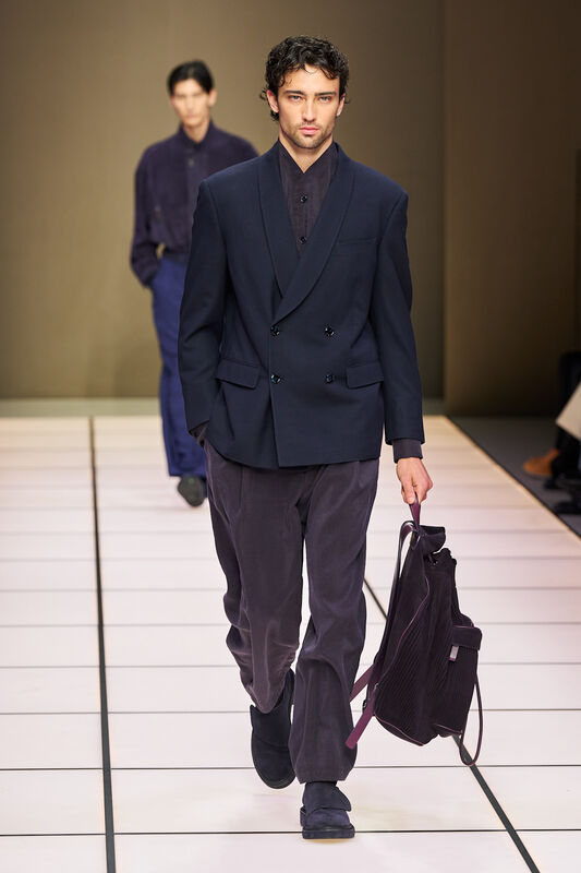 Мужская двойка в темно-синем цвете с текстурированным пиджаком, дополненная стильной сумкой и уверенным взглядом