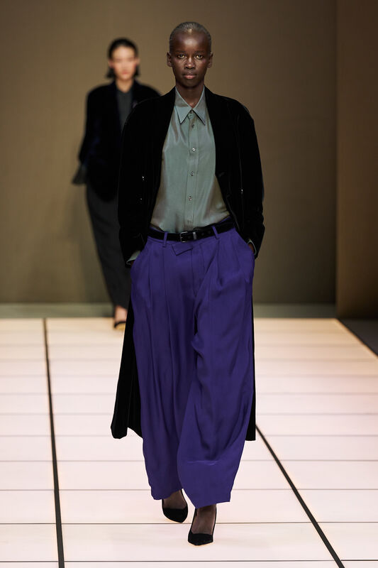 Модель в черном бархатном пальто и светло-зеленой рубашке, гармонично дополняет яркие синие брюки