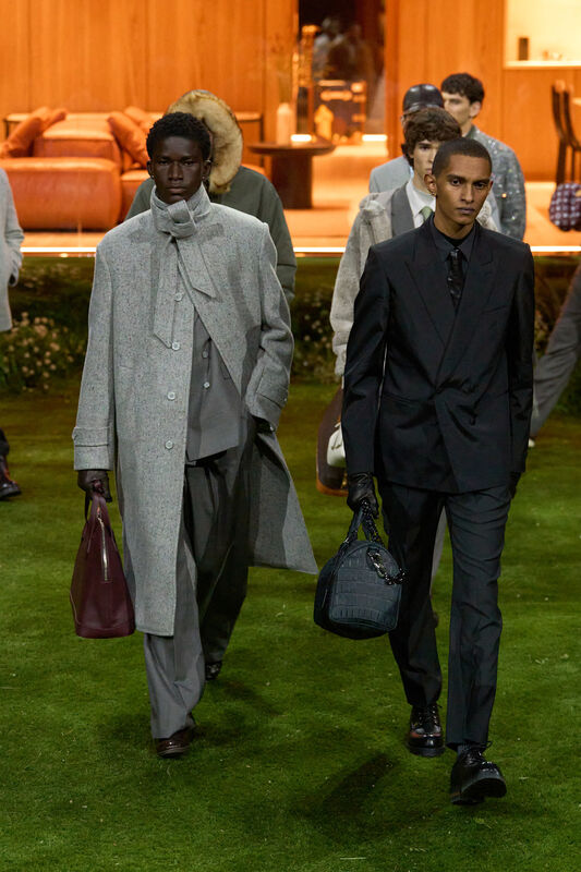 Модели в стильных нарядах от Louis Vuitton: серый пальто с текстурой и черный смокинг, подчеркивающие элегантность осени.