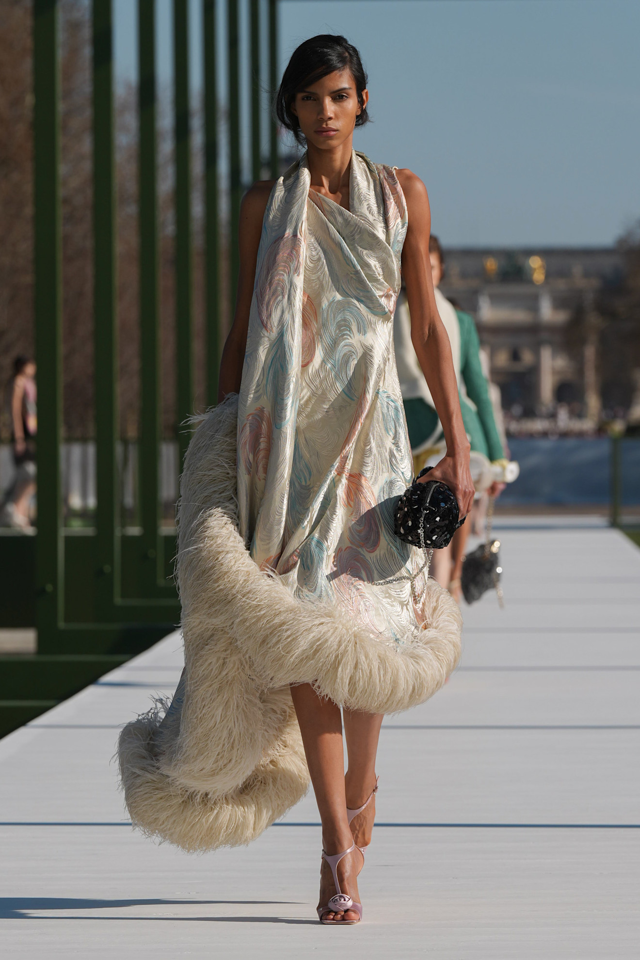 Элегантное платье с абстрактным узором и меховой отделкой, дополненное черной сумочкой, излучает роскошь и утонченность