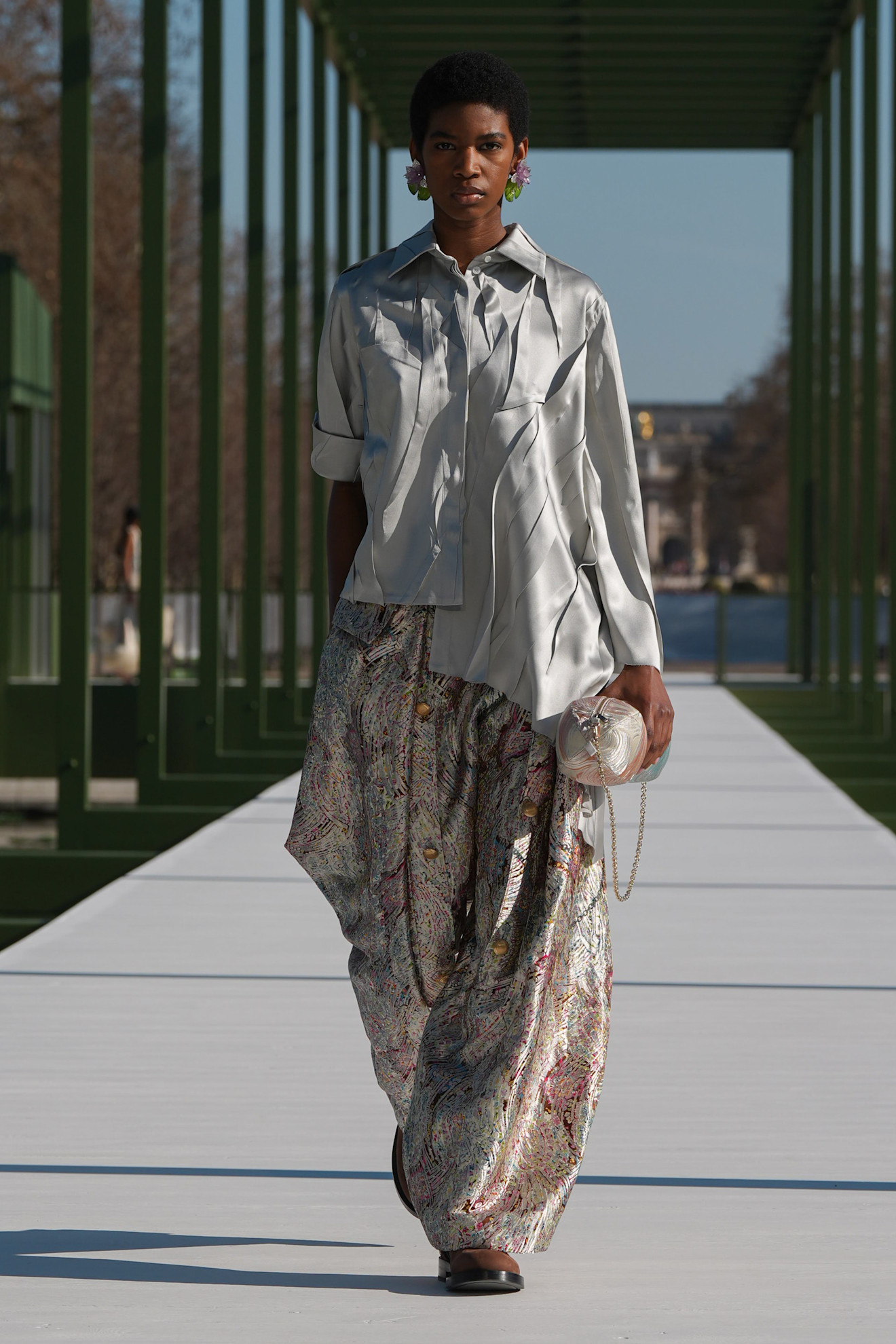 Серебристая рубашка с волнистым дизайном и широкие брюки с цветным узором, придающие образу легкость и изысканность