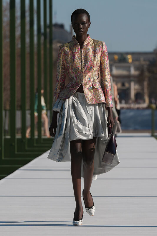 Яркий жакет с узором и асимметричная юбка, создающие динамичный образ, дополненный стильной сумкой и обувью с принтом