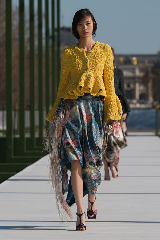 Яркий желтый жакет с рюшами в сочетании с цветным юбкой, создаёт игривый и весенний образ