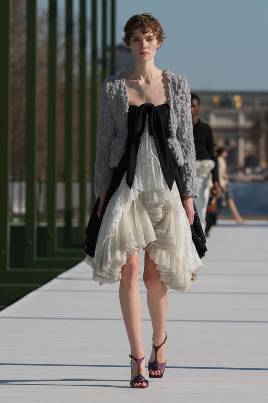 Серый жакет с черным бантом и легкая юбка с рюшами, гармонично сочетающие строгость и игривость