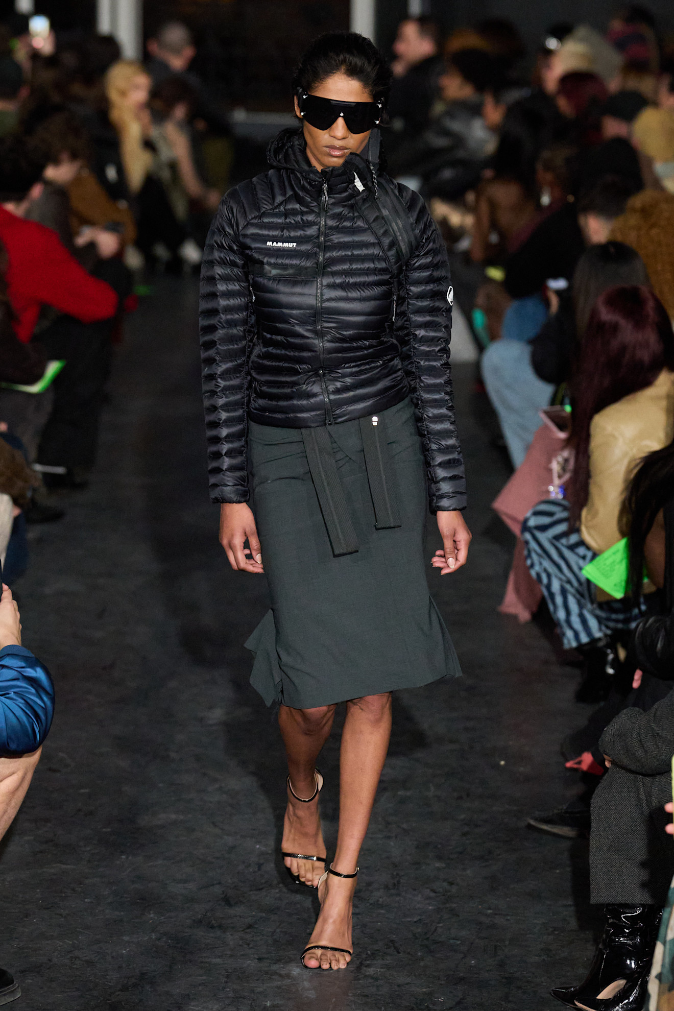Модель в стеганой куртке и юбке, завершает образ темными очками, создавая современный и утонченный стиль