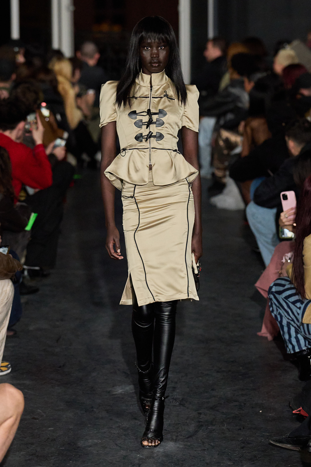 Модель в бежевом платье с пышной юбкой и черными кожаными леггинсами, акцент на силуэт и текстуру