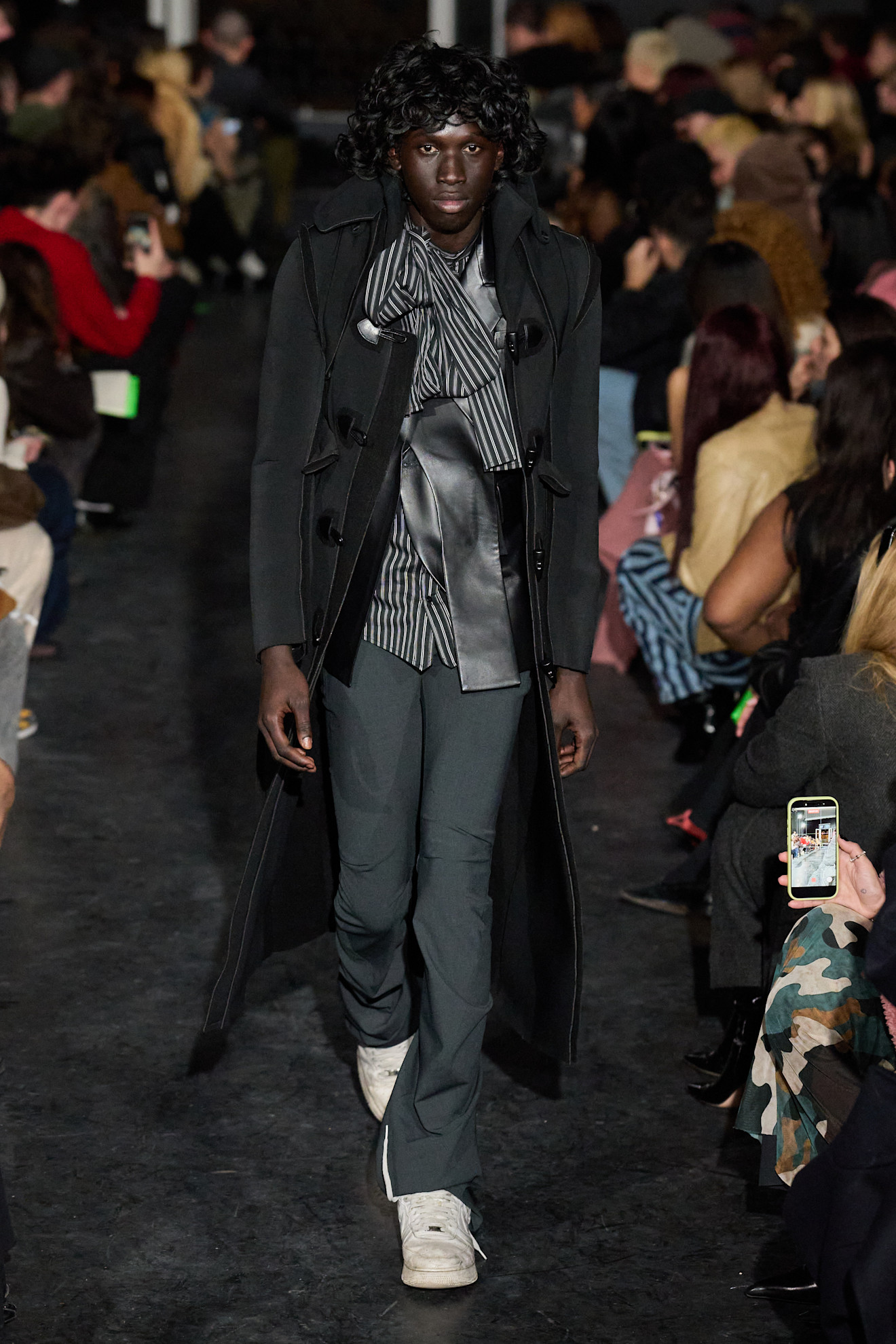 Черное пальто с полосатой рубашкой и брюками, дополненное кроссовками, создает элегантный и утонченный образ