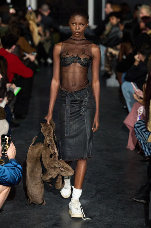 Прозрачный топ с черной кружевной отделкой и джинсовая юбка, дополненные меховым аксессуаром для смелого стиля