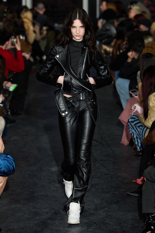 Девушка в облегающем черном кожаном костюме с асимметричным кроем, демонстрирует смелый и дерзкий образ