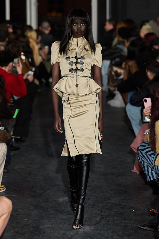 Модель в бежевом платье с пышной юбкой и черными кожаными леггинсами, акцент на силуэт и текстуру