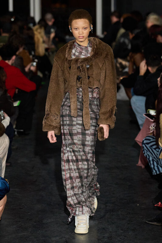 Комбинация коричневого меха и клетчатого платья, завершает образ белыми кроссовками, создавая контраст стилей