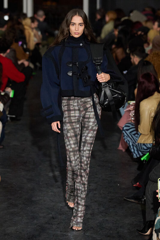 Элегантное сочетание тёмного пальто и облегающих штанов в клетку, подчеркивающее силуэт и утонченность
