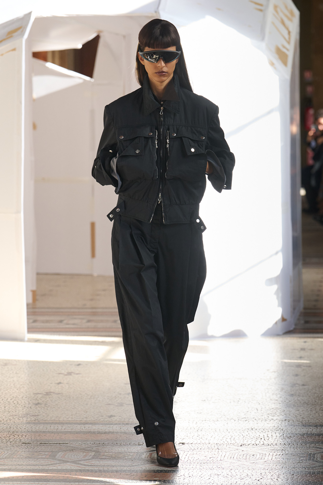 Строгий черный комплект с укороченной курткой и широкими брюками, дополненный эффектными очками и лаконичными линиями