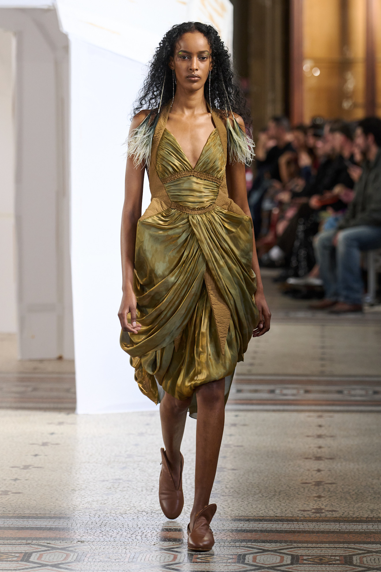 Золотистое платье с драпировкой и перьевыми акцентами, создающее эффект легкости и изысканности