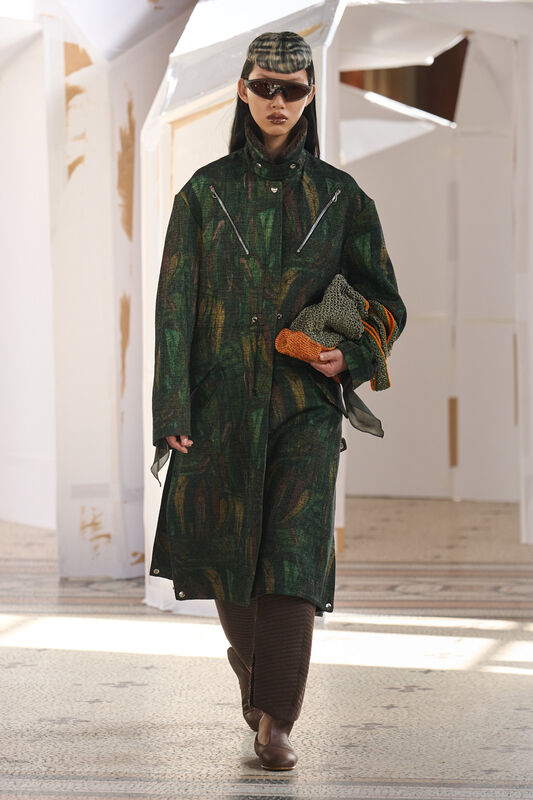 Длинное пальто с текстурой и яркими акцентами, дополненное стильными аксессуарами, создает образ уверенной и модной женщины