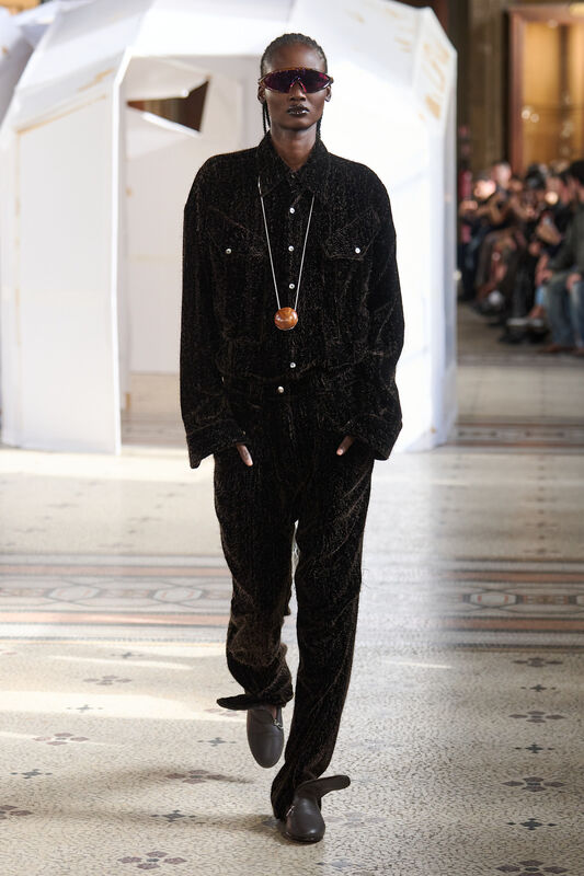 Элегантный образ в черном бархатном костюме с крупными карманами и стильными солнцезащитными очками, подчеркивающий уверенность