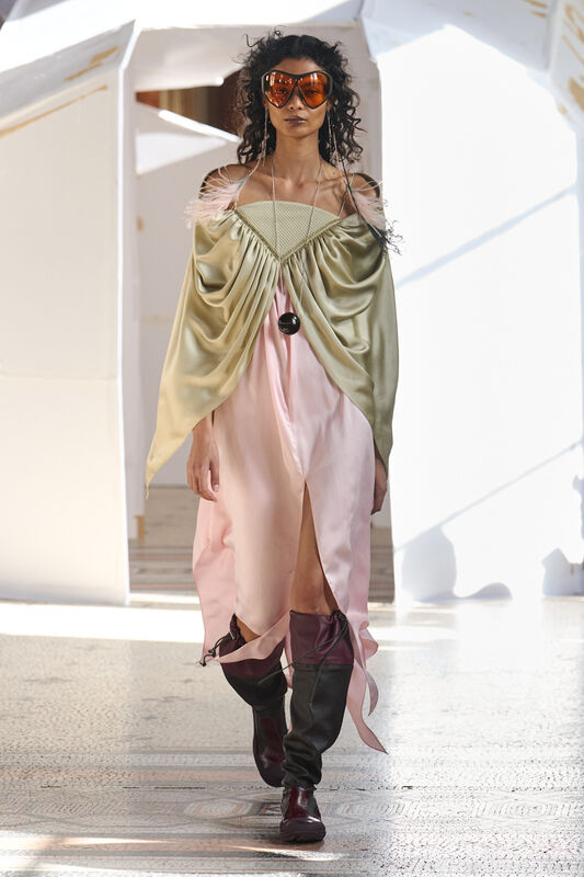 Модель в платье с зеленым верхом и розовой юбкой, украшенным перьями, завершает образ стильными очками