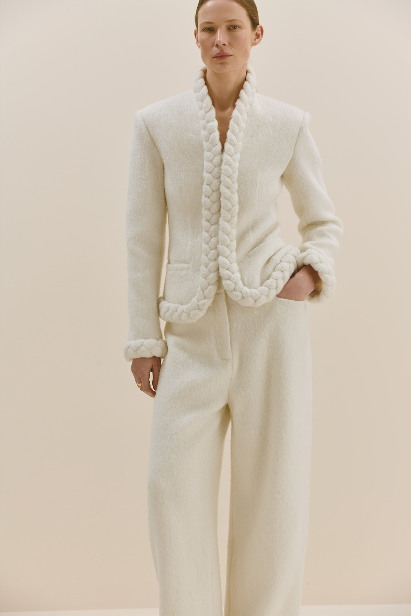 Элегантный белый костюм с плетеными деталями на лацканах и манжетах, подчеркивающий утонченность силуэта.