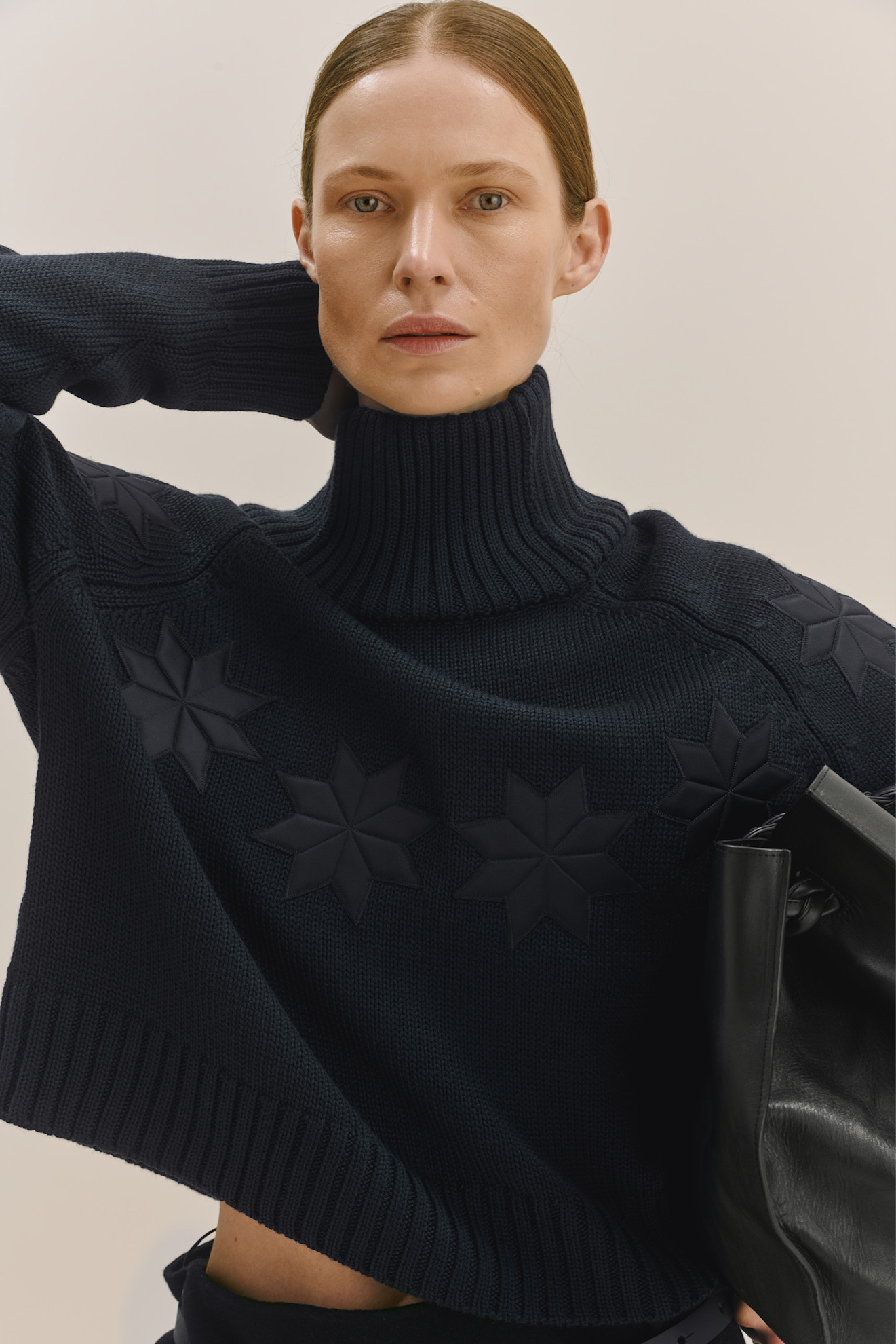 Темно-синий свитер с высоким воротником и рельефными звездами, строгий стиль с акцентом на детали