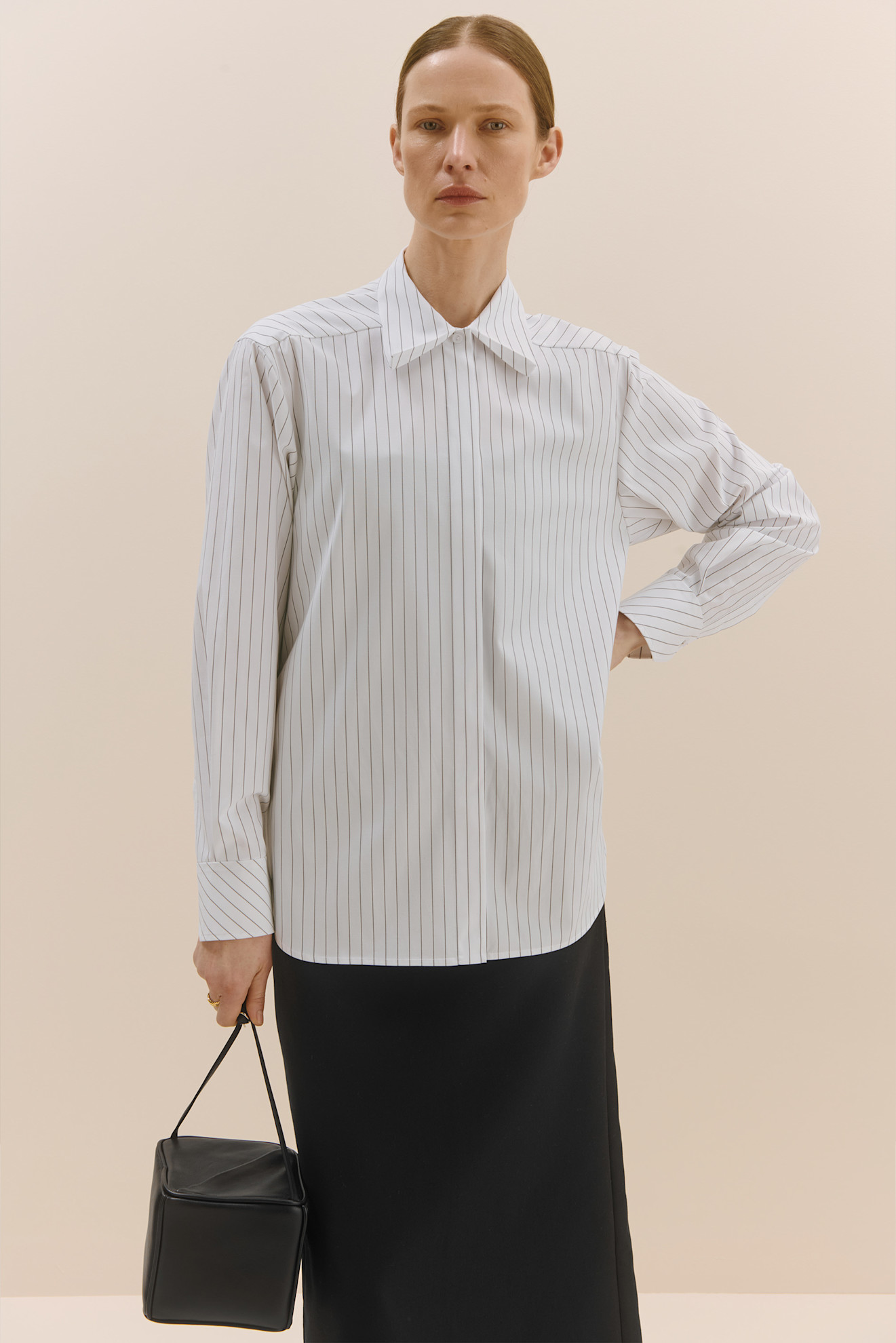 Строгая белая рубашка в тонкую полоску с широким воротником, дополненная черной юбкой и сумкой