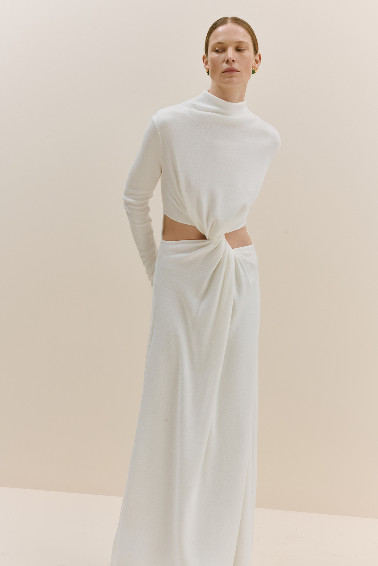 Элегантное белое платье с высоким воротником и открытой талией, создающее эффект струящейся ткани