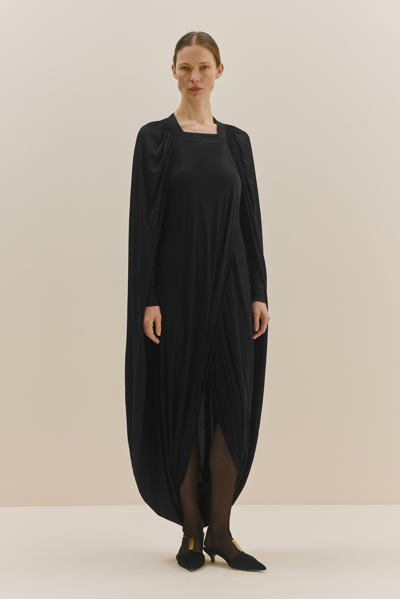 Черное платье с длинным рукавом и драпировкой, создающее загадочный и драматичный силуэт