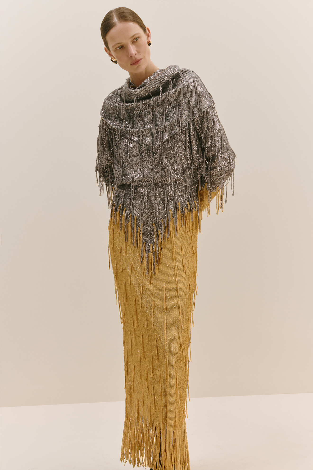 Блестящий топ с бахромой из серебристых пайеток, дополненный золотой юбкой, создаёт эффектный контраст текстур и цветов