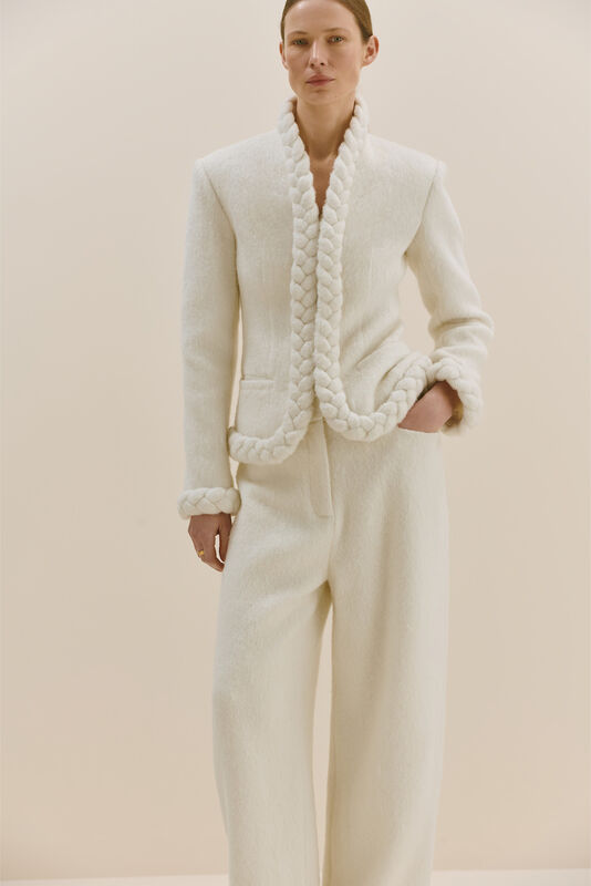 Элегантный белый костюм с плетеными деталями на лацканах и манжетах, подчеркивающий утонченность силуэта.