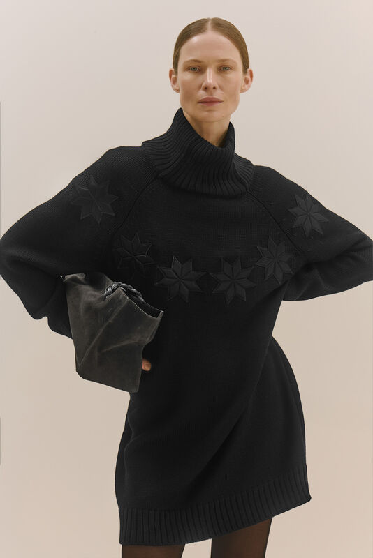 Черный свитер-туника с высоким воротником и рельефными звездами, дополненный стильной сумкой для завершения образа