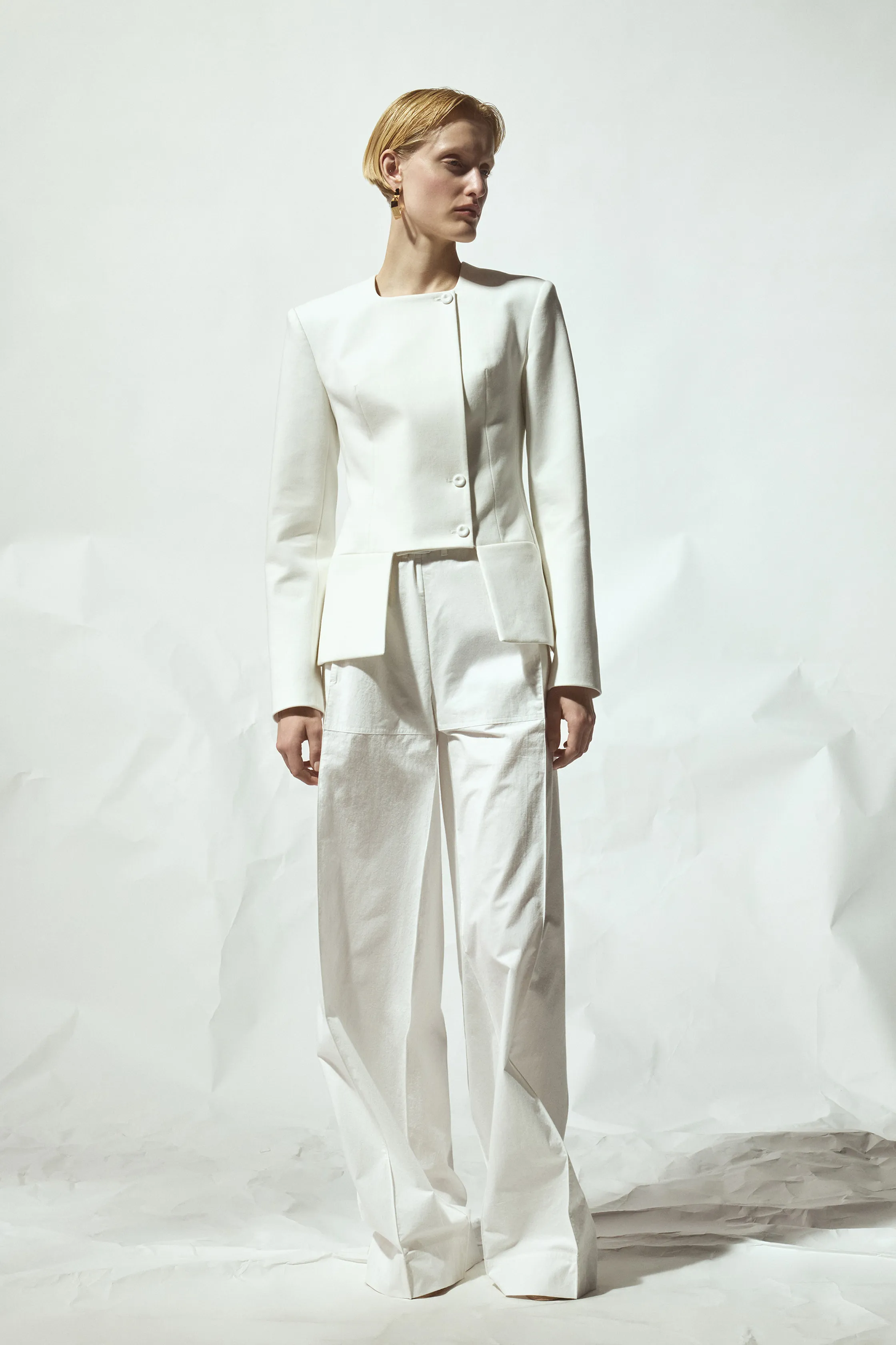 Строгий белый костюм с жакетом и широкими брюками, подчеркивающий современный стиль и уверенность модели