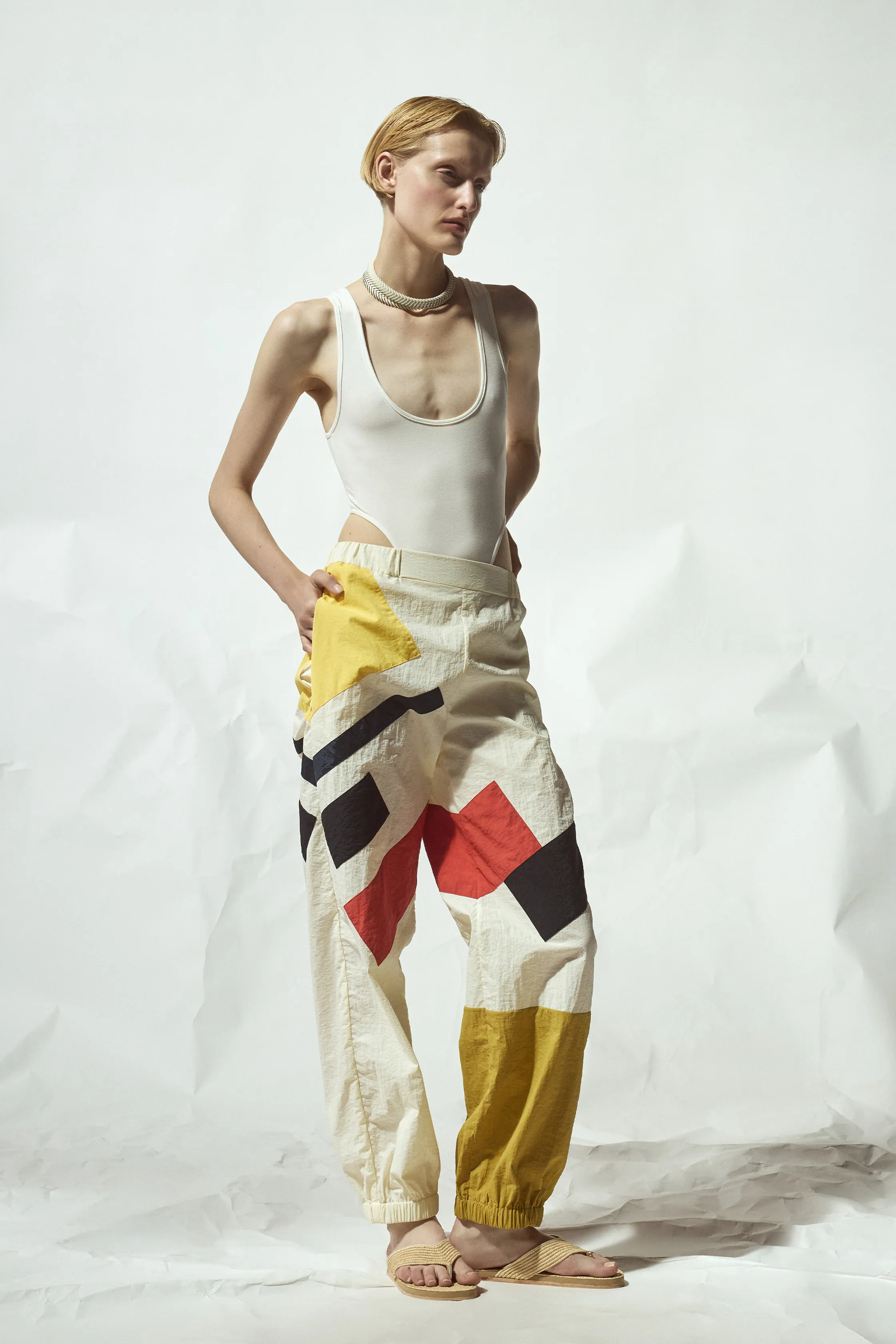 Яркие брюки с геометрическим принтом в желтых и красных тонах, дополненные простым белым топом для смелого образа