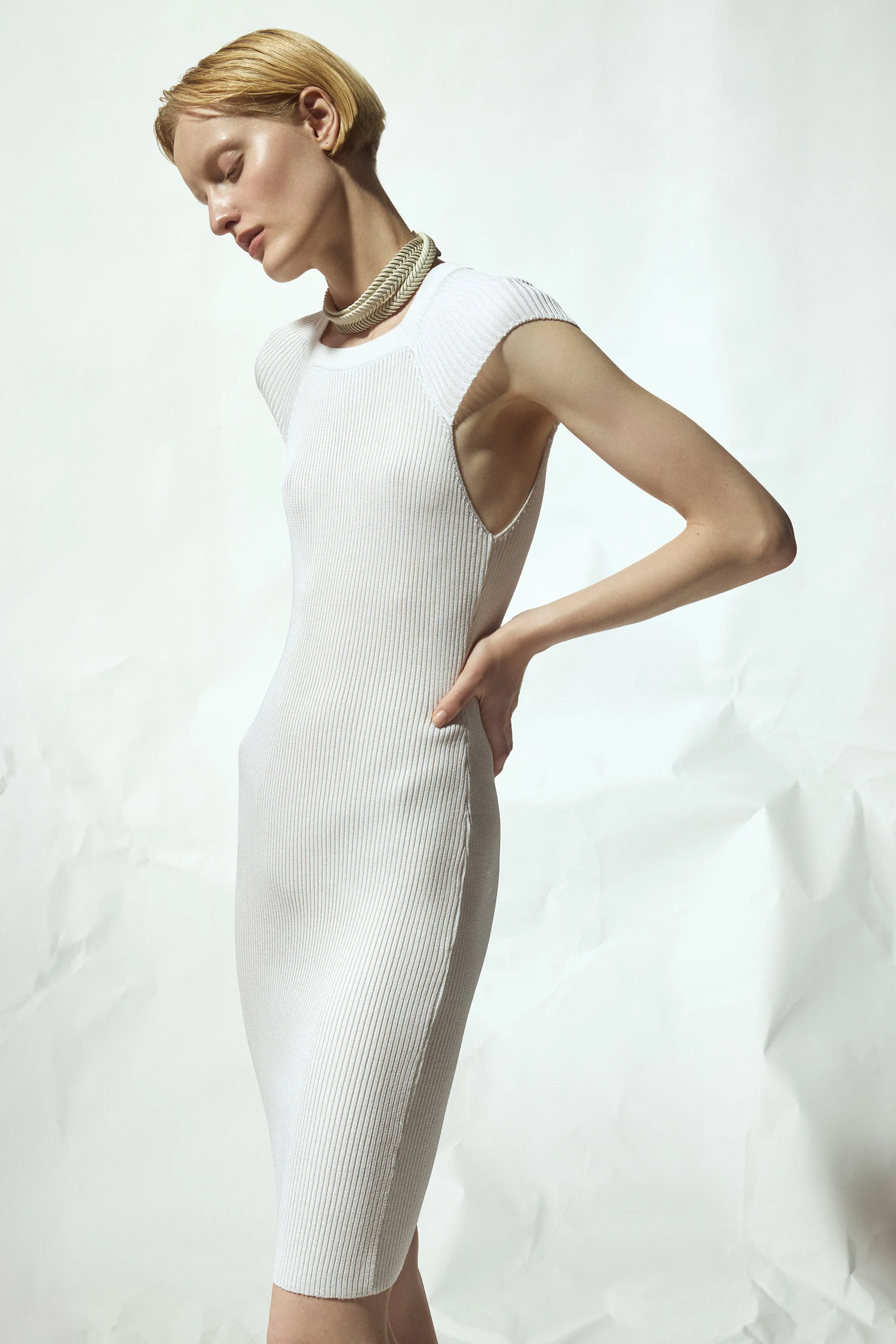 Обтягивающее белое платье с рельефной текстурой и открытыми плечами, создающее эффектный силуэт