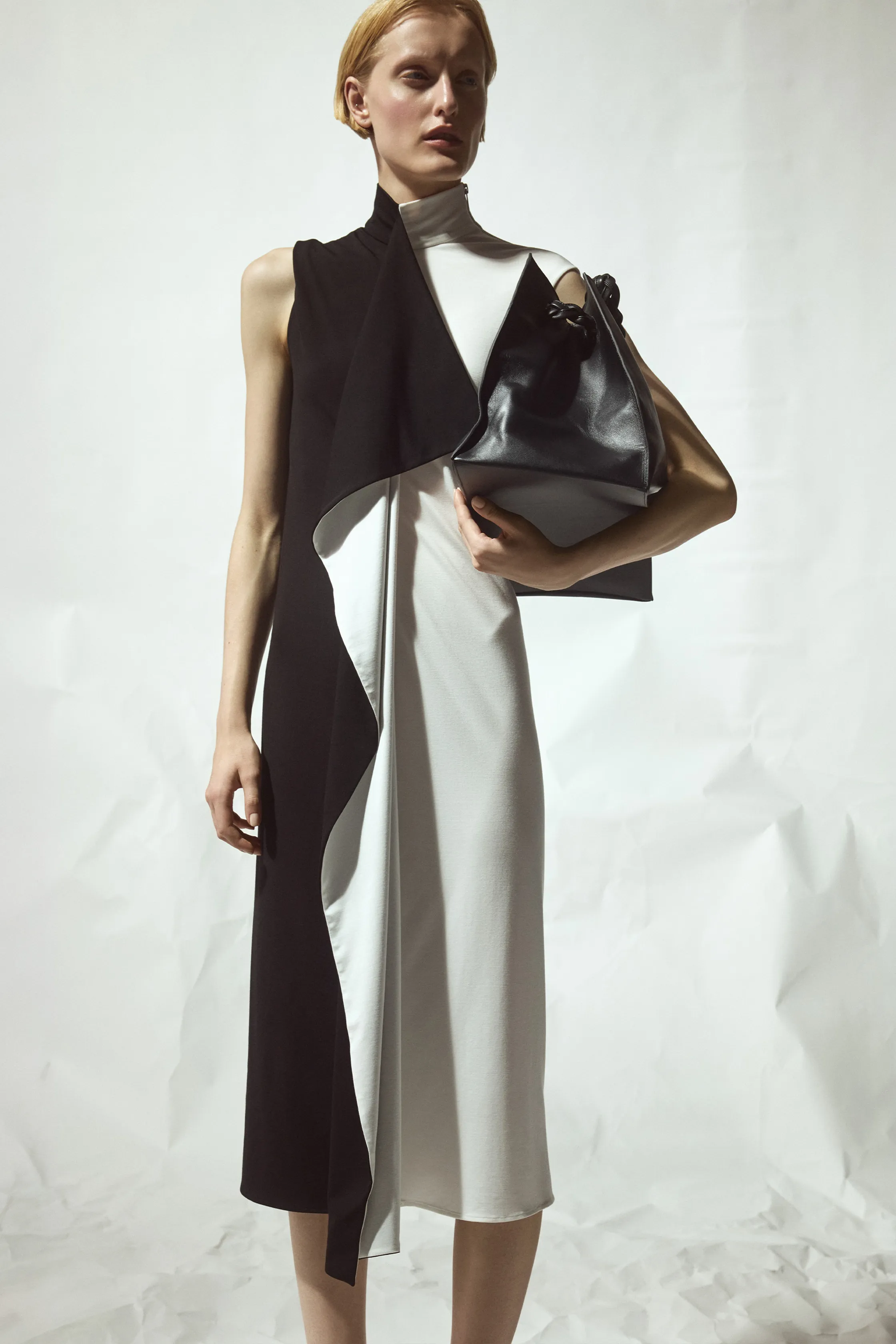 Двухцветное платье с асимметричным кроем в черно-белых тонах, дополненное стильной сумкой для завершения образа