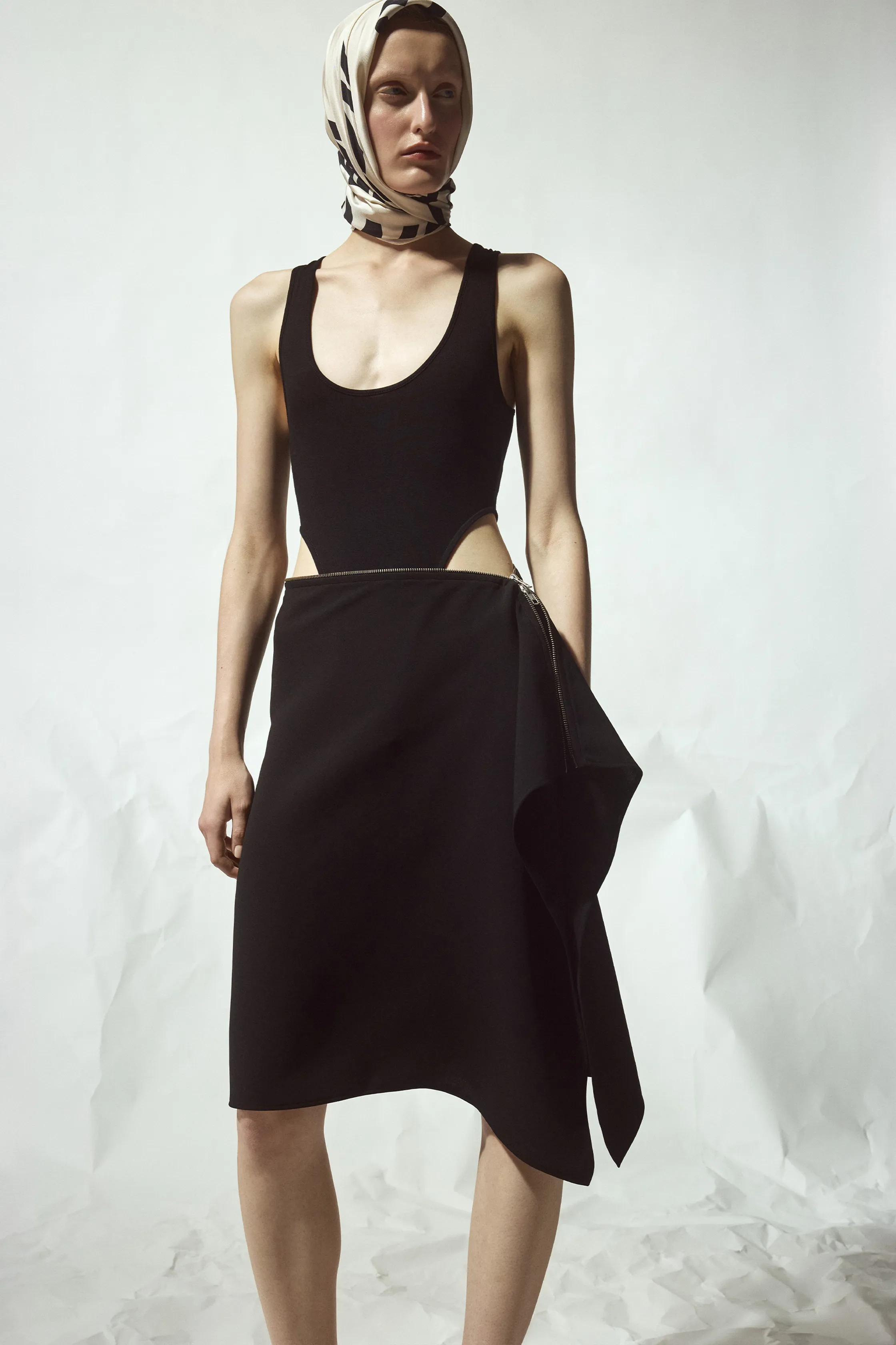 Минималистичный черный наряд с вырезами и шейным платком, подчеркивающий силуэт и элегантность модели