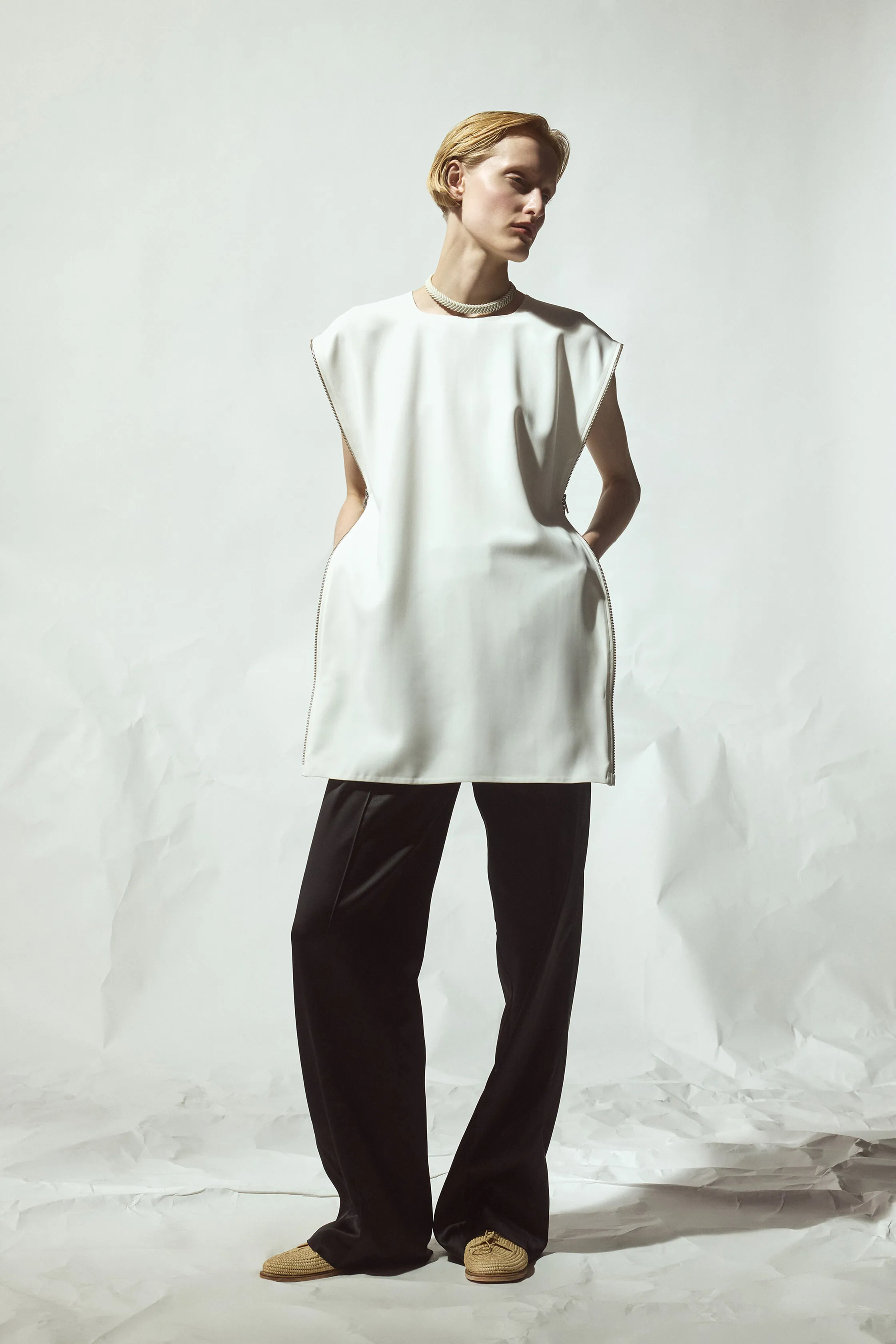 Белая туника с объемными рукавами и карманами, гармонично сочетающаяся с черными брюками, создавая стильный контраст