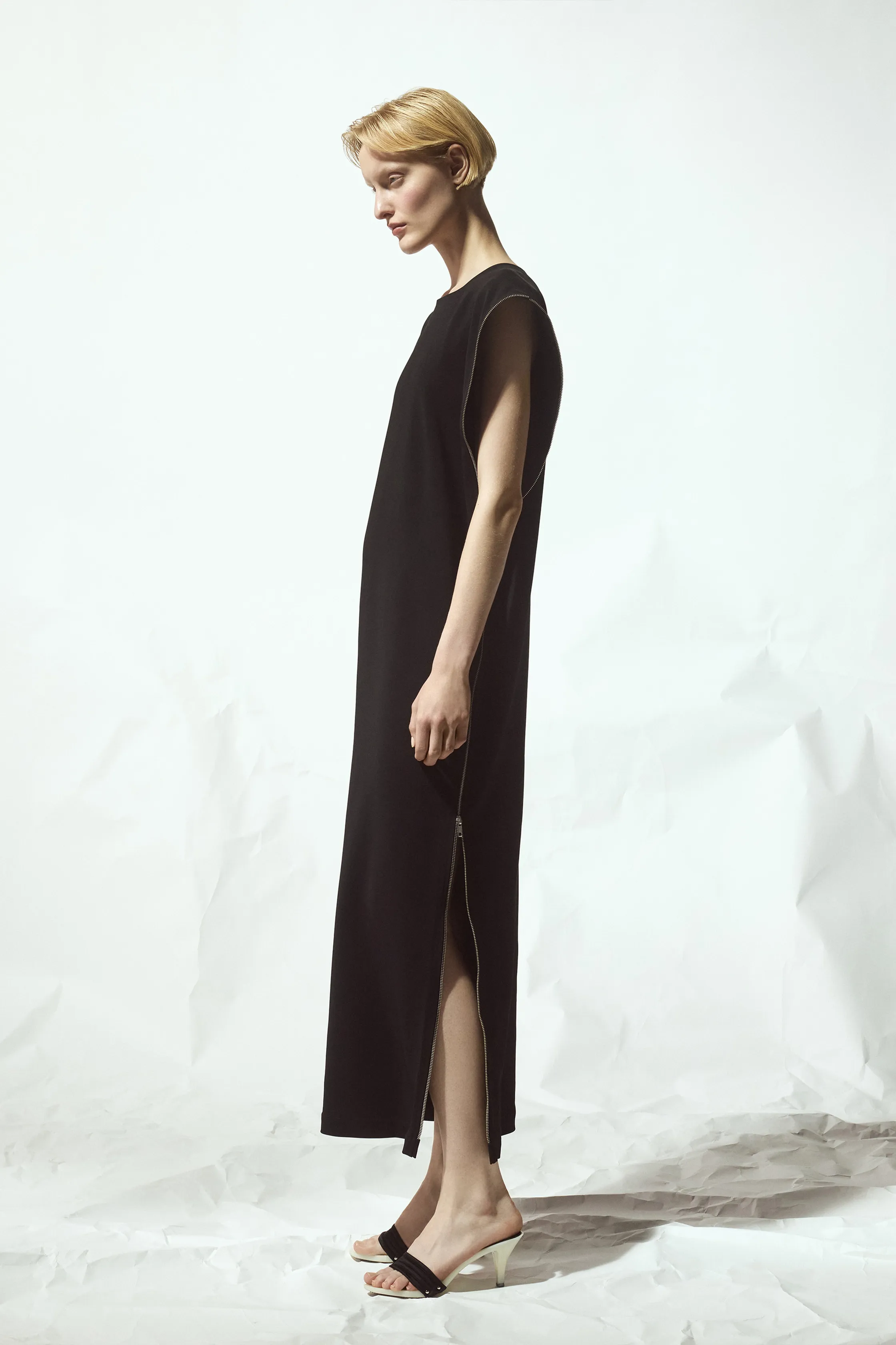 Простое черное платье с длинными боковыми разрезами и минималистичным дизайном, подчеркивающее утонченность и стиль модели
