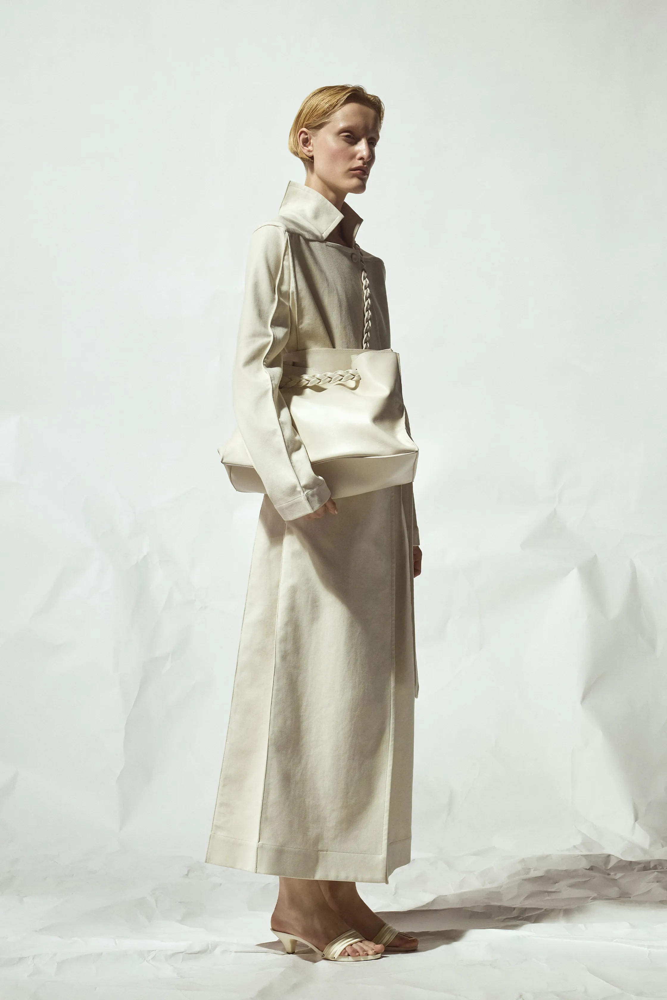 Строгий наряд из светлого материала с высоким воротником и объемной сумкой, подчеркивающий утонченность образа