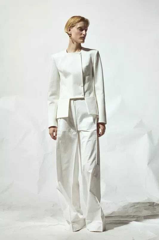 Строгий белый костюм с жакетом и широкими брюками, подчеркивающий современный стиль и уверенность модели
