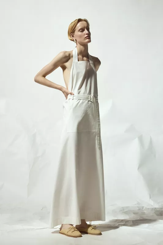 Элегантное белое платье-апрон с открытыми плечами, подчеркивающее утонченность и легкость весеннего стиля