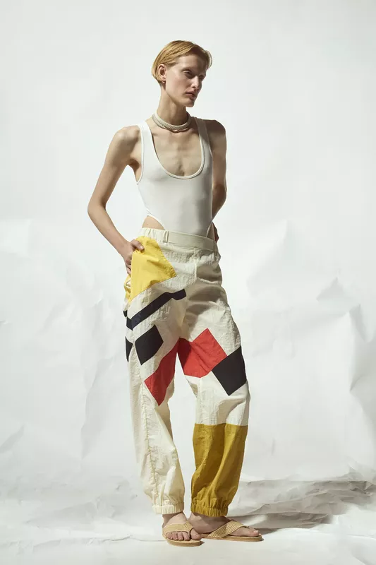 Яркие брюки с геометрическим принтом в желтых и красных тонах, дополненные простым белым топом для смелого образа