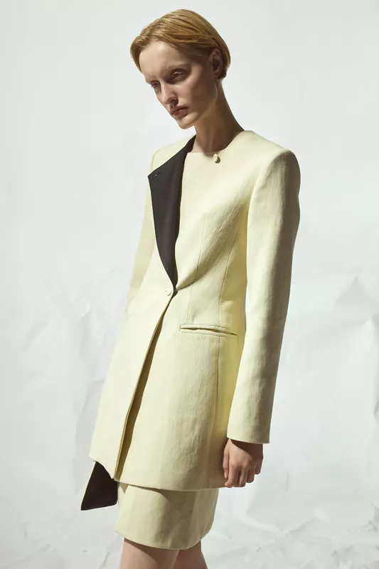 Легкий жакет с асимметричным черным лацканом и короткой юбкой в нежном лимонном оттенке, создающий элегантный силуэт