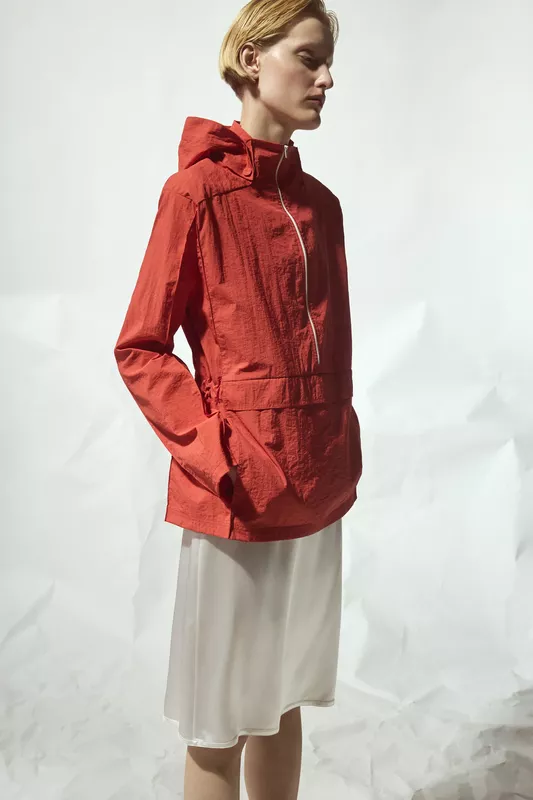 Яркая красная куртка с капюшоном и утонченным кроем, дополненная легким белым платьем, создающим свежий весенний образ