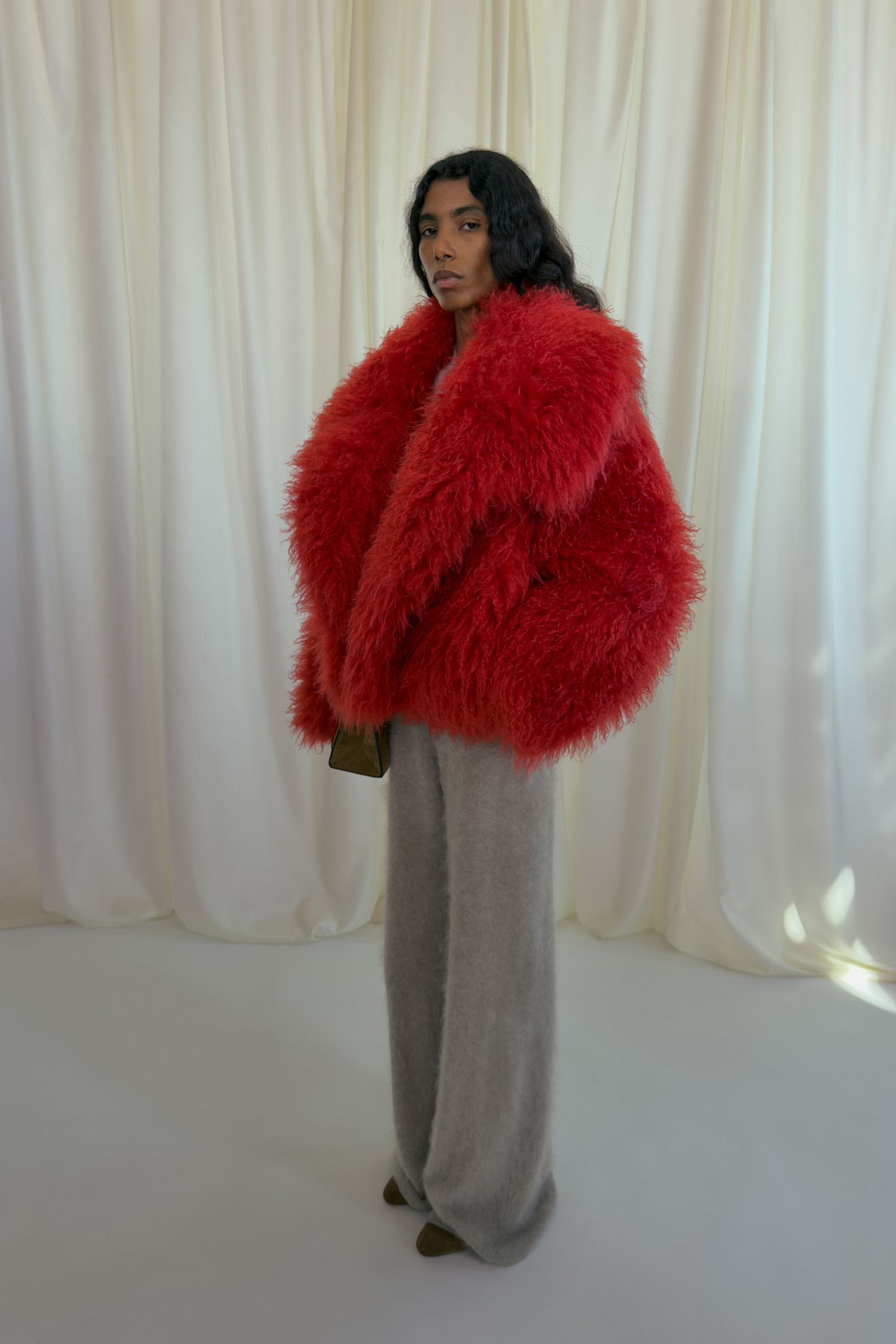 Объемный красный пуховик с длинными рукавами и серыми широкими брюками, создающий эффект уютной тепла