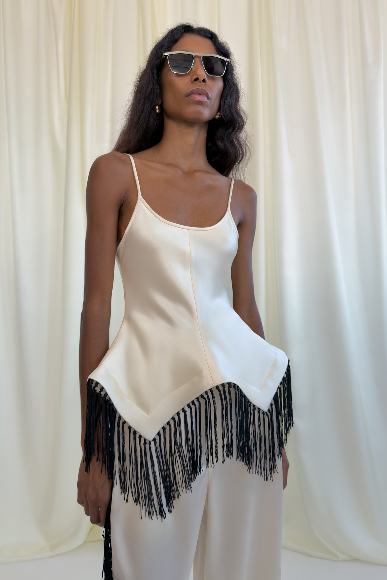 Шелковый топ с черной бахромой и тонкими бретелями, дополненный стильными солнцезащитными очками