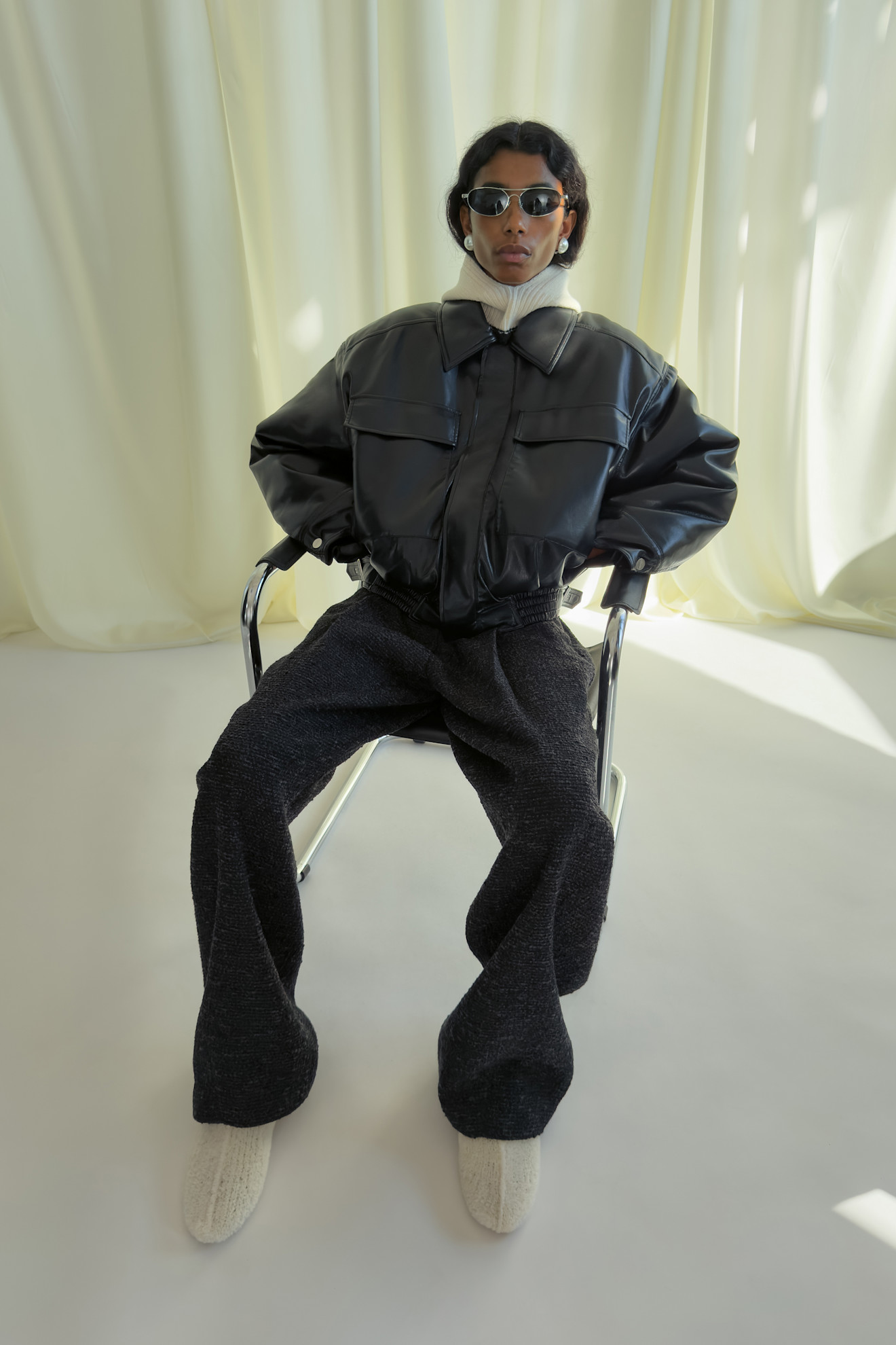 Объемная черная куртка с высокими карманами и светлым воротником, сочетание с серыми брюками и уютными тапочками