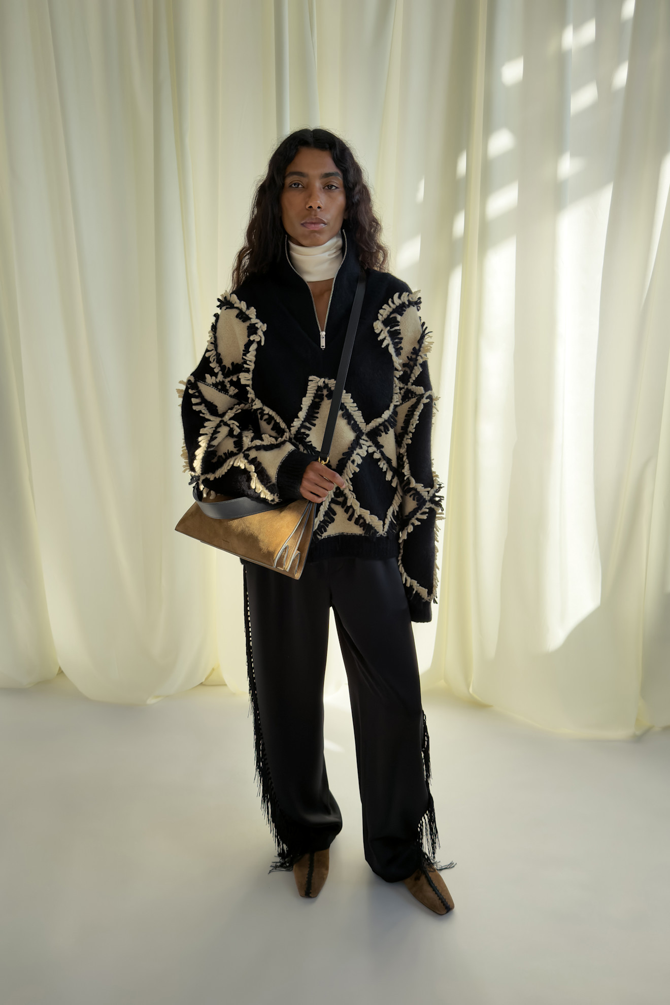 Уютный черно-белый свитер с геометрическим узором, дополненный черными брюками и металлической сумкой для завершения образа