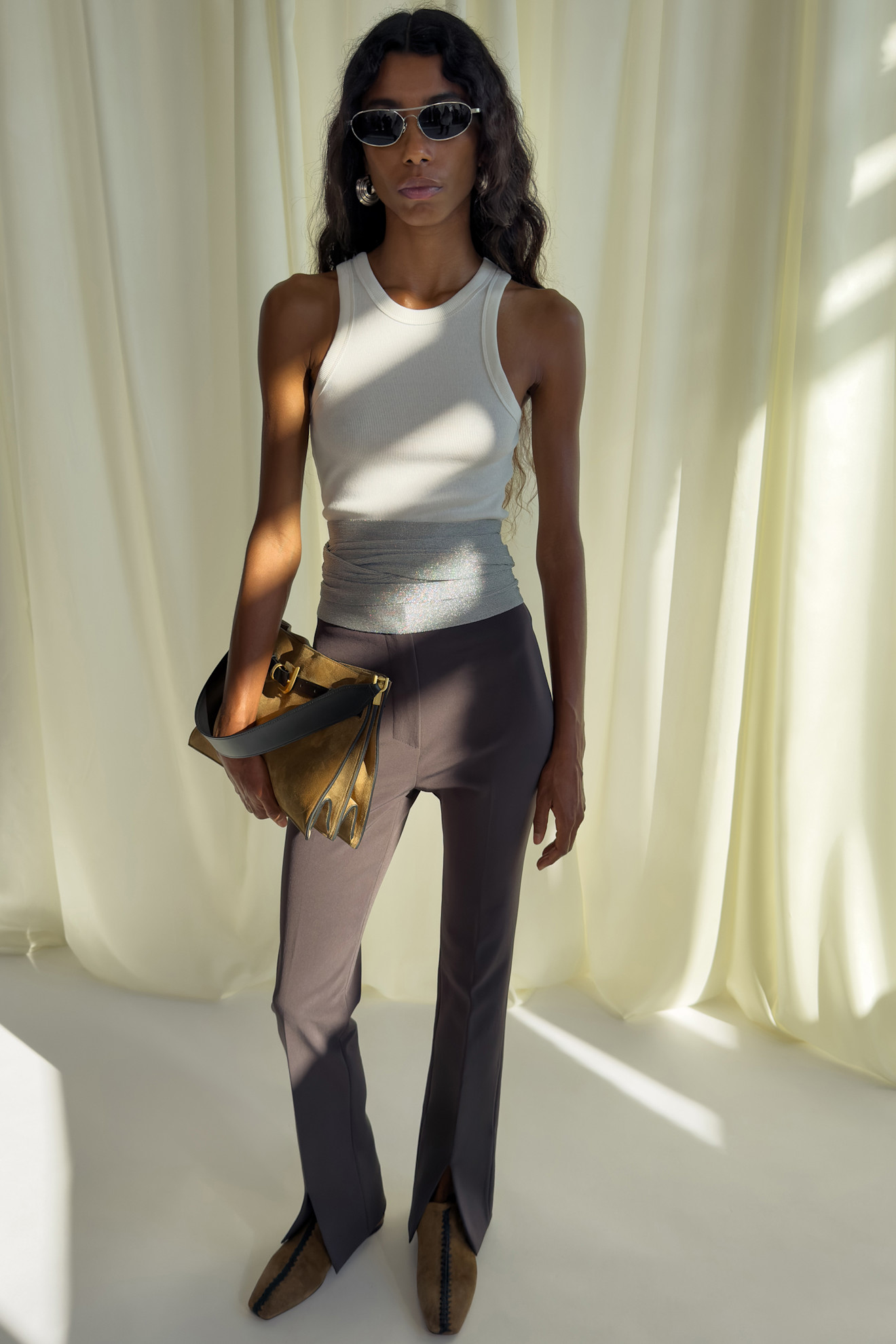 Стильный образ с облегающим топом и брюками с разрезами, дополненный золотистой сумкой и солнцезащитными очками
