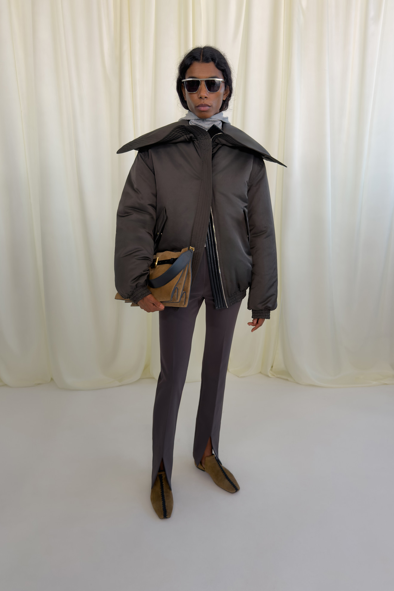 Модный лук с объемной курткой и строгими брюками с разрезами, дополненный стильной сумкой и солнечными очками