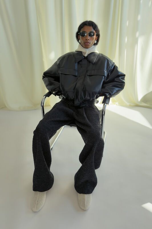 Объемная черная куртка с высокими карманами и светлым воротником, сочетание с серыми брюками и уютными тапочками